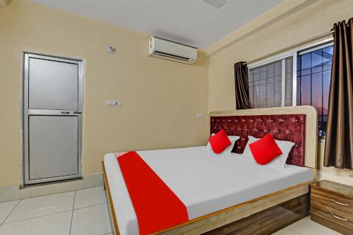 Schlafzimmer mit einem Bett mit roten Kissen und einem Fenster in der Unterkunft OYO Flagship 81208 Jagarnath Palace in Ranchi