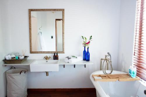 um banheiro com uma pia, um espelho e uma banheira em The Blue Place em Pretoria