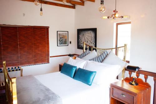um quarto com uma cama com lençóis brancos e almofadas azuis em The Blue Place em Pretoria