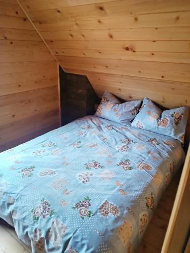 a bed in a log cabin with a blue comforter at Vila Planinski san 1 in Zaovine