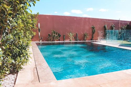 a swimming pool next to a red wall at Villa Alma, luxueuse villa au cœur de Marrakech in Marrakesh