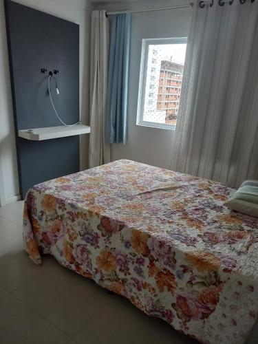 een slaapkamer met een bed met een bloemendeken bij Cleverson Machado in Itapema