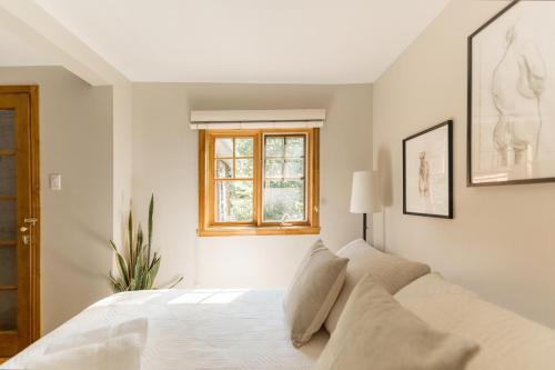 um quarto com uma cama branca e uma janela em Auberge Yoga Salamandre em Lac-Brome