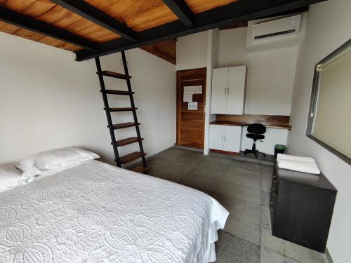 a bedroom with a bed and a ladder and a desk at Casa Ilhe Ha in Santa María Tonameca