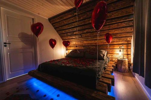 a bedroom with red balloons and a bed with a wooden wall at Upea hirsi mökki ulkoporeltaalla sekä kelosaunalla in Hämeenlinna