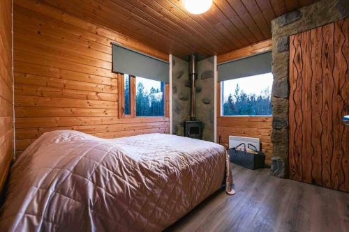 1 dormitorio con 1 cama en una cabaña de madera en Upea hirsi mökki ulkoporeltaalla, en Hämeenlinna