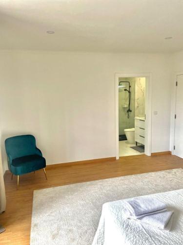 a bedroom with a blue chair and a bathroom at LouriVillage in Lourinhã