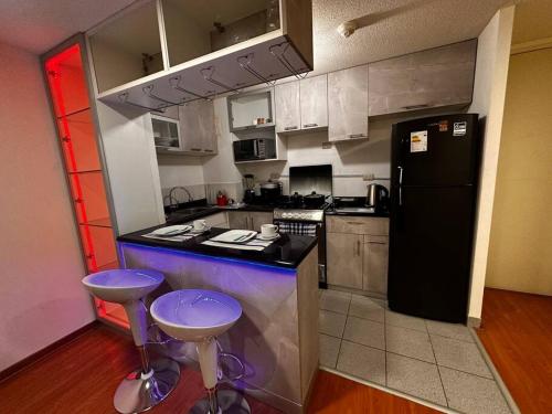 una cucina con frigorifero nero e 2 sgabelli di Apartamento completo en Callao a Lima
