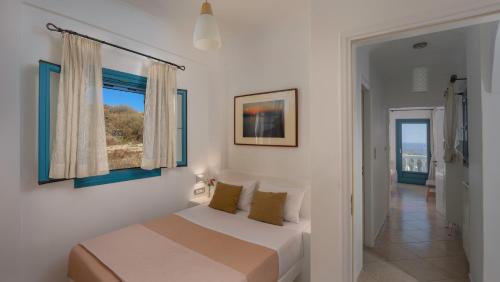a white bedroom with a bed and a window at Skarmoutsos Holiday Home in Vourvoulos