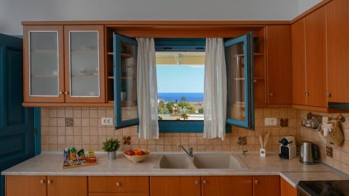 een keuken met een wastafel en een raam bij Skarmoutsos Holiday Home in Vourvoúlos