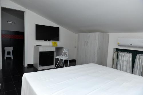 Schlafzimmer mit einem weißen Bett und einem Flachbild-TV in der Unterkunft HOTEL POSIDONIA INN SAPRI in Sapri
