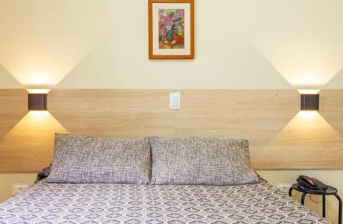 a bedroom with a bed with two lights on it at Hotel Saveiros in Ubatuba