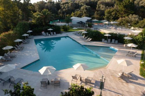 una vista sul soffitto di una piscina con sedie e ombrelloni di Nafsika Hotel - Adults Only a Dassia