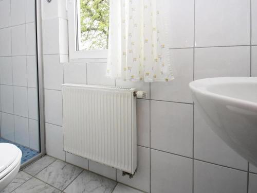 a bathroom with a radiator and a sink and a window at Cottage on the Kummerower See, Kummerow in Kummerow