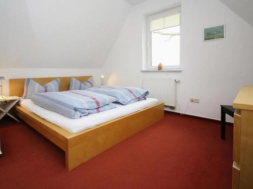een slaapkamer met een bed met blauwe kussens en een raam bij Cottage on the Kummerower See, Kummerow in Kummerow