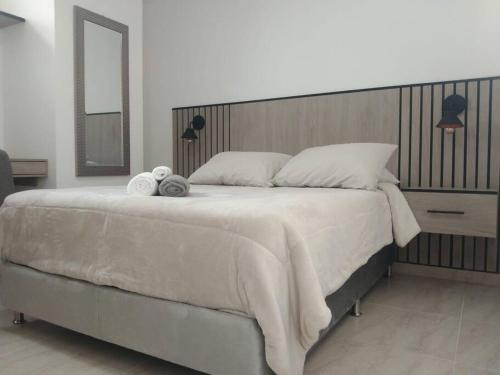 1 dormitorio con 1 cama grande y 2 toallas. en Acogedor apartamento con sala de TV, en Sabaneta