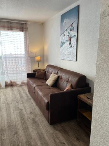 a brown leather couch in a living room with a window at Chalet L'Hermine in Val Thorens