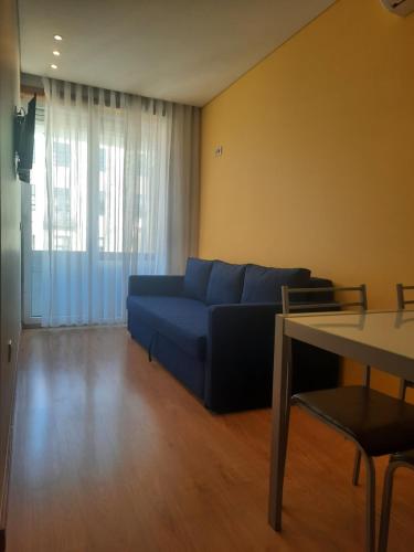 a living room with a blue couch and a table at Apartamentos Portodouro - Santa Catarina in Porto