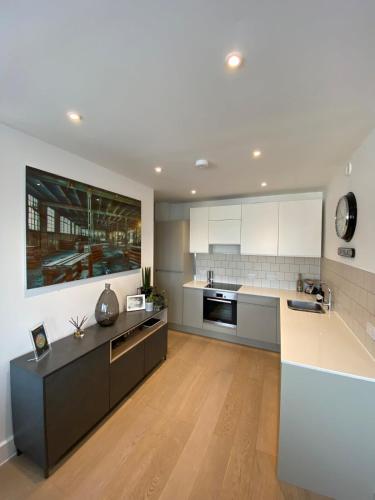 uma cozinha com armários brancos e uma bancada em Tasteful 2BD Flat wOpen Plan Living - Blackheath! em Londres