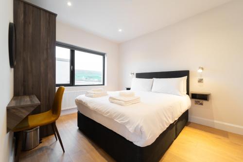 Dingle Way Snug, Luxury apartment في دينغل: غرفة نوم بسرير وكرسي ونافذة