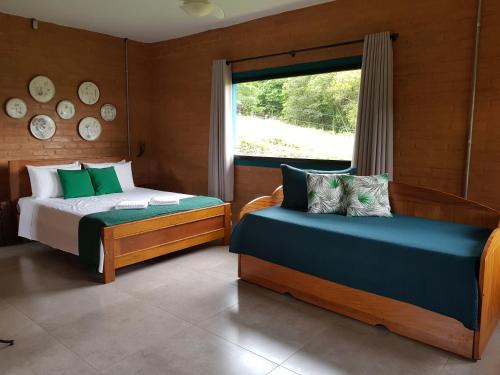 a bedroom with two beds and a window at Pousada Fazenda Vitoria in São João Batista do Glória