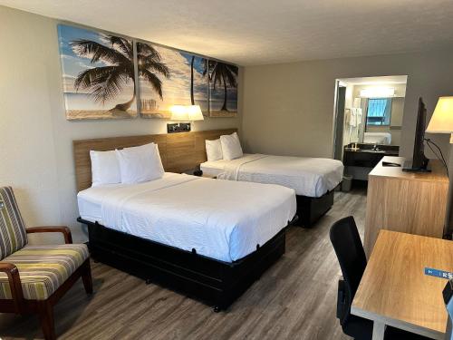 a hotel room with two beds and a chair at Days Inn by Wyndham St Augustine I-95-Outlet Mall in St. Augustine