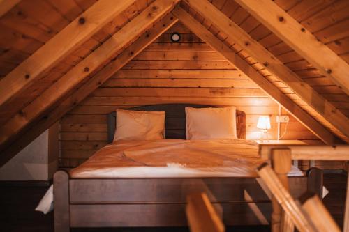 a bed in the attic of a wooden house at Vikendica MINI in Jotanovići