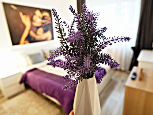 un jarrón lleno de flores púrpuras en un dormitorio en Relaxing Coresi Place en Braşov