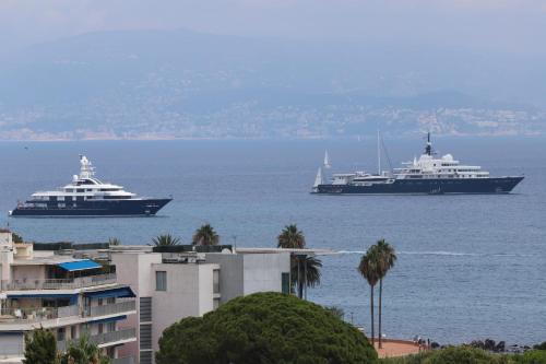 deux grands navires dans l'eau à côté d'un bâtiment dans l'établissement Pretty haven of peace with sea view, à Antibes