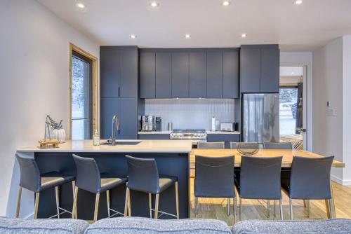 a kitchen with blue cabinets and a bar with chairs at Snohaus 9 - Scandinavian Mountain Chalet in Mont-Tremblant