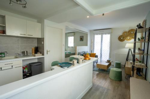 a kitchen with white cabinets and a counter with green chairs at Le Zéphyr - Tout équipé - Wifi - Parking gratuit in Saint-Nazaire