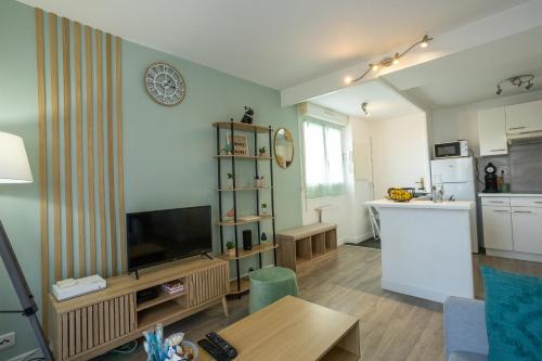 Il comprend un salon avec une télévision et une cuisine. dans l'établissement Le Zéphyr - Charme Urbain & Confort, à Saint-Nazaire