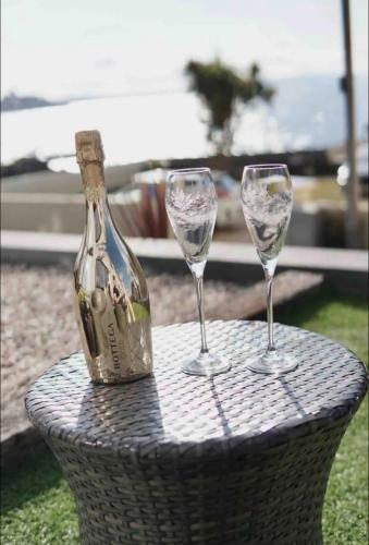 two wine glasses and a bottle on a table at Contemporary Seaside Apartment in Bangor