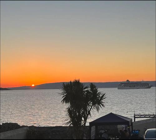 a cruise ship in the water at sunset at Contemporary Seaside Apartment in Bangor