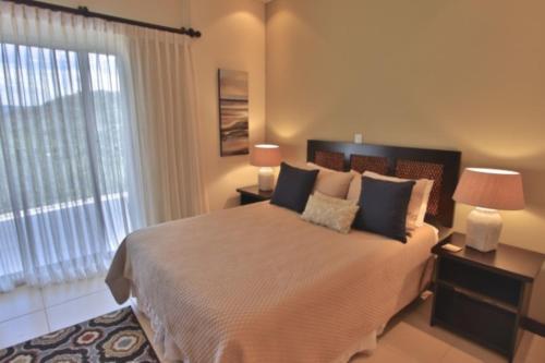 a bedroom with a large bed with two lamps and a window at Playa Flamingo - 2 BR condo with great ocean views - FLAMINGO TOWERS 25 in Playa Flamingo