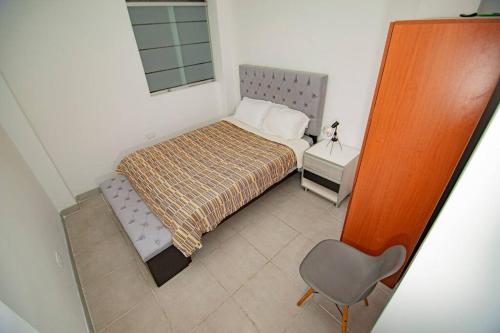 a small bedroom with a bed and a chair at Moderno y acogedor departamento in Tacna