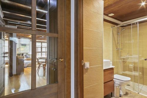 La salle de bains est pourvue de toilettes et d'une porte en verre. dans l'établissement Luderna - Apartamento Val de Ruda B15 Baretja, à Baqueira-Beret
