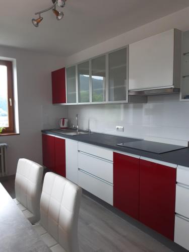 a kitchen with red and white cabinets and a sink at EROPLAN in Ružomberok