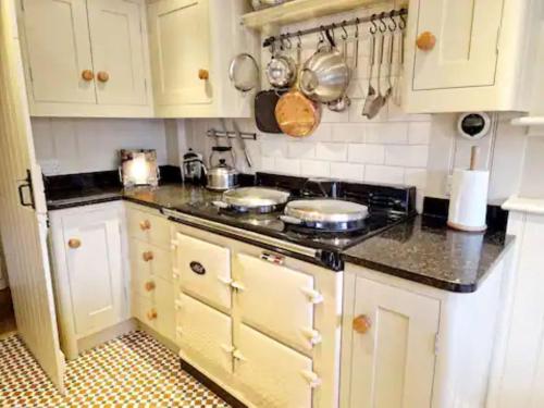 a kitchen with white cabinets and a stove top oven at Jackdaw Cottage-Beautiful Cottage, Town Centre in Wimborne Minster