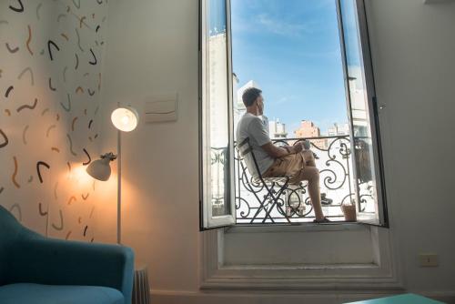 a man sitting in a chair looking out of a window at Viajero Montevideo Hostel in Montevideo