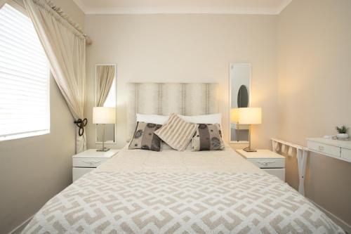 a white bedroom with a large bed with two lamps at Shepherd's Rest in Mossel Bay