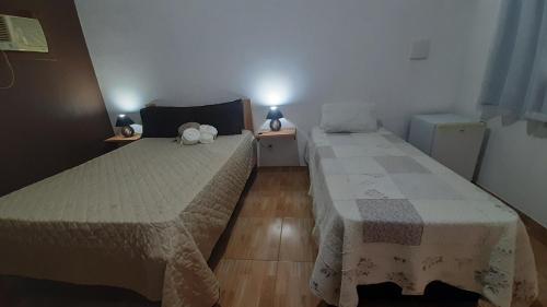 two beds in a small room with two tables at Rancho Esperança, pouso e comida a lenha in Paraty