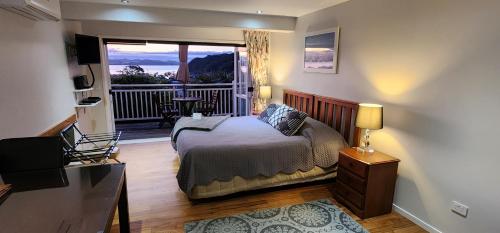a bedroom with a bed and a balcony with a view at Bellrock Lodge in Russell
