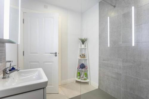 a white bathroom with a sink and a shower at Modern Apartment Portrush in Portrush