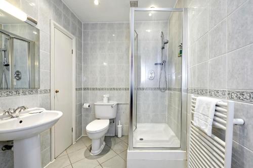a bathroom with a toilet sink and a shower at Historic Whitehall flat in SW1 by UnderTheDoormat in London