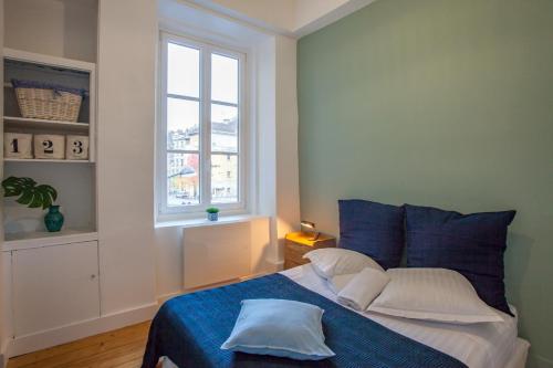 um quarto com uma cama com lençóis azuis e uma janela em Sur les Traces du chevalier Bayard em Grenoble