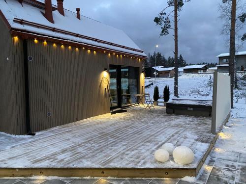 a building with a deck in the snow at Guesthouse with sauna & hot tub & cold water pool in Nokia