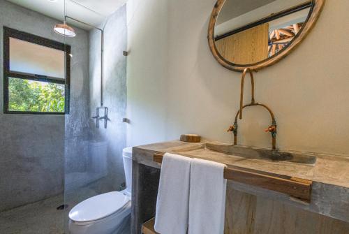 La salle de bains est pourvue d'un lavabo, de toilettes et d'un miroir. dans l'établissement Raíz Hotel Boutique, à Puerto Escondido
