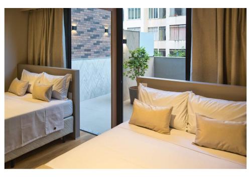 a bedroom with two beds with pillows and a balcony at Life Residence in Belo Horizonte
