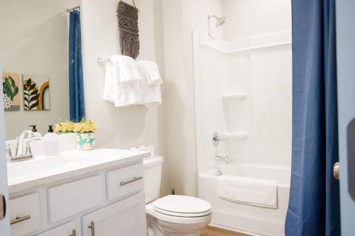 a white bathroom with a toilet and a sink and a tub at Charming Brand New Home in Foley in Foley
